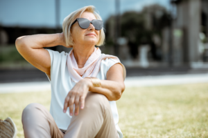 Woman with sahes sitting outside, enjoying the sunlight